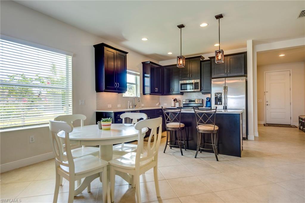 3782 Canopy Circle Naples, FL 34120 - Photo 14 of 31 a kitchen with granite countertop a dining table chairs and a refrigerator