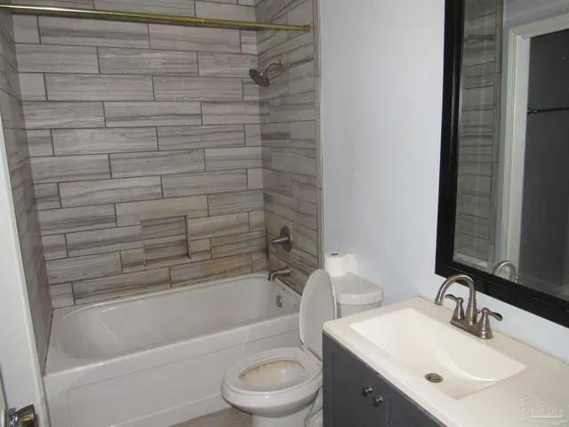 a bathroom with a bathtub shower sink vanity mirror and toilet
