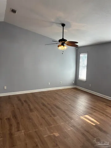 a view of an empty room with window and chandelier fan