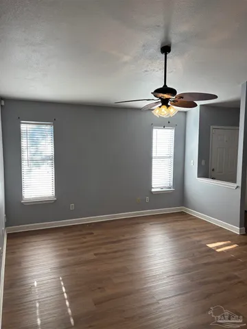 a view of an empty room with window and wooden floor