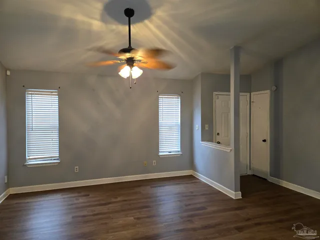 a view of an empty room with a window and wooden floor