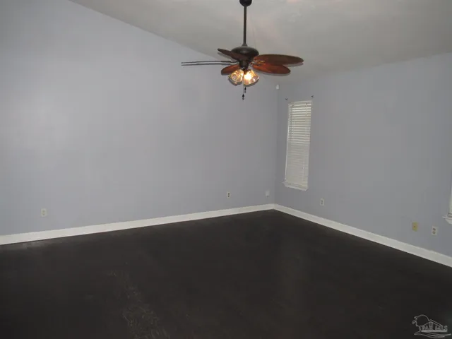 a view of a room with hardwood floor a ceiling fan and a window