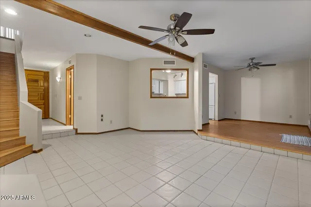 an empty room with ceiling fan and windows