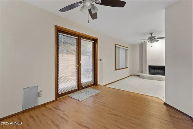 a view of an empty room with wooden floor and a ceiling fan