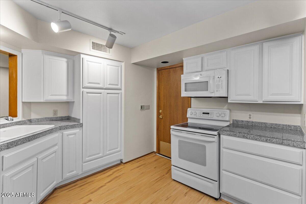 5750 North 10th Street, Unit 5 Phoenix, AZ 85014 - Photo 18 of 37 a kitchen with white cabinets and white appliances
