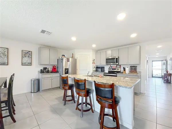 a kitchen with a dining table chairs and refrigerator