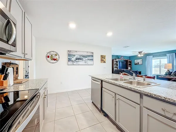 a kitchen with stainless steel appliances granite countertop a table chairs microwave and refrigerator