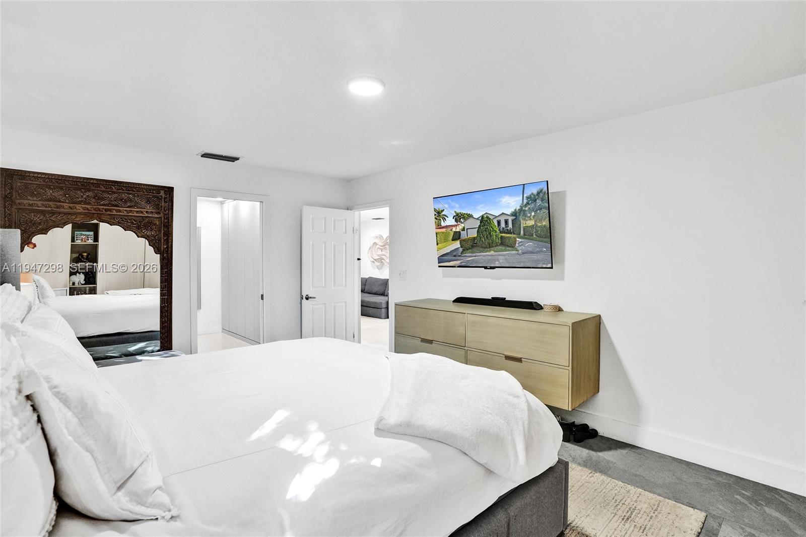 9181 Byron Avenue Surfside, FL 33154 - Photo 15 of 51 a bedroom with a large bed and a flat tv screen on dresser