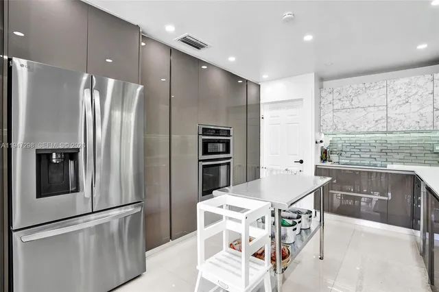 a kitchen with stainless steel appliances kitchen island granite countertop a refrigerator and a stove top oven