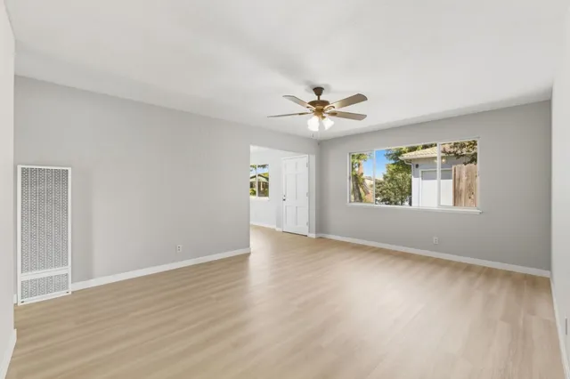 a view of an empty room with a window and wooden floor