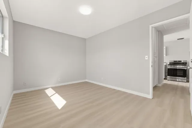 a view of empty room with wooden floor and kitchen