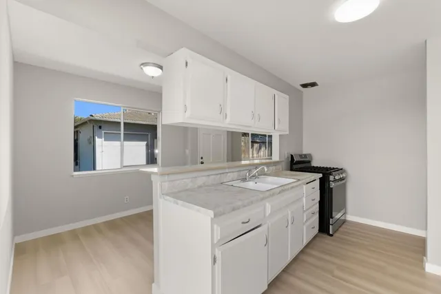 a kitchen with stainless steel appliances granite countertop a sink and cabinets with wooden floor