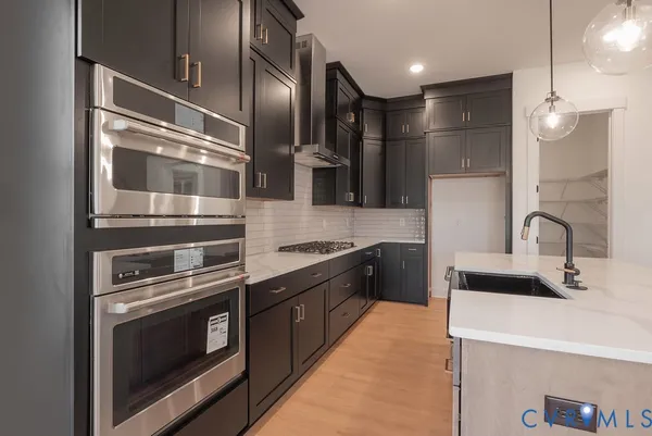 a large kitchen with a large stove a sink dishwasher a refrigerator and a oven with wooden floor