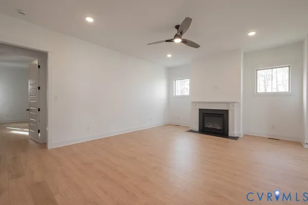 a view of an empty room with a window and wooden floor