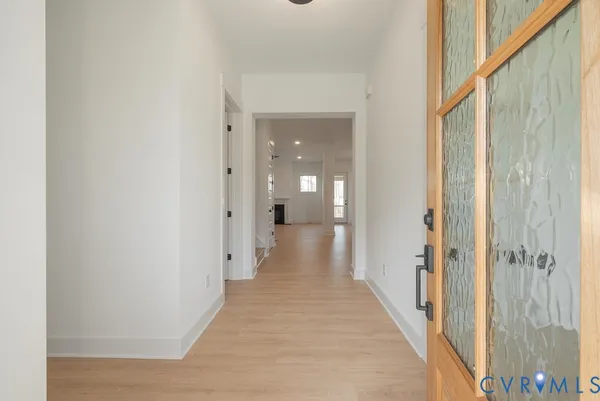 a view of a hallway with wooden floor and a bathroom