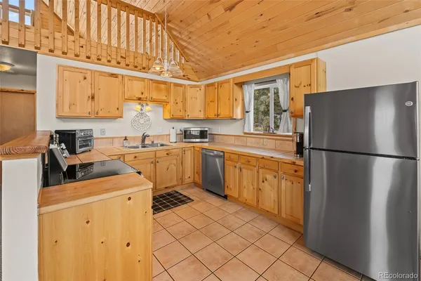 a kitchen with stainless steel appliances granite countertop a stove a sink dishwasher and a refrigerator with wooden floor
