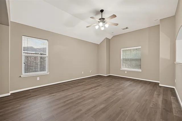 an empty room with wooden floor and windows