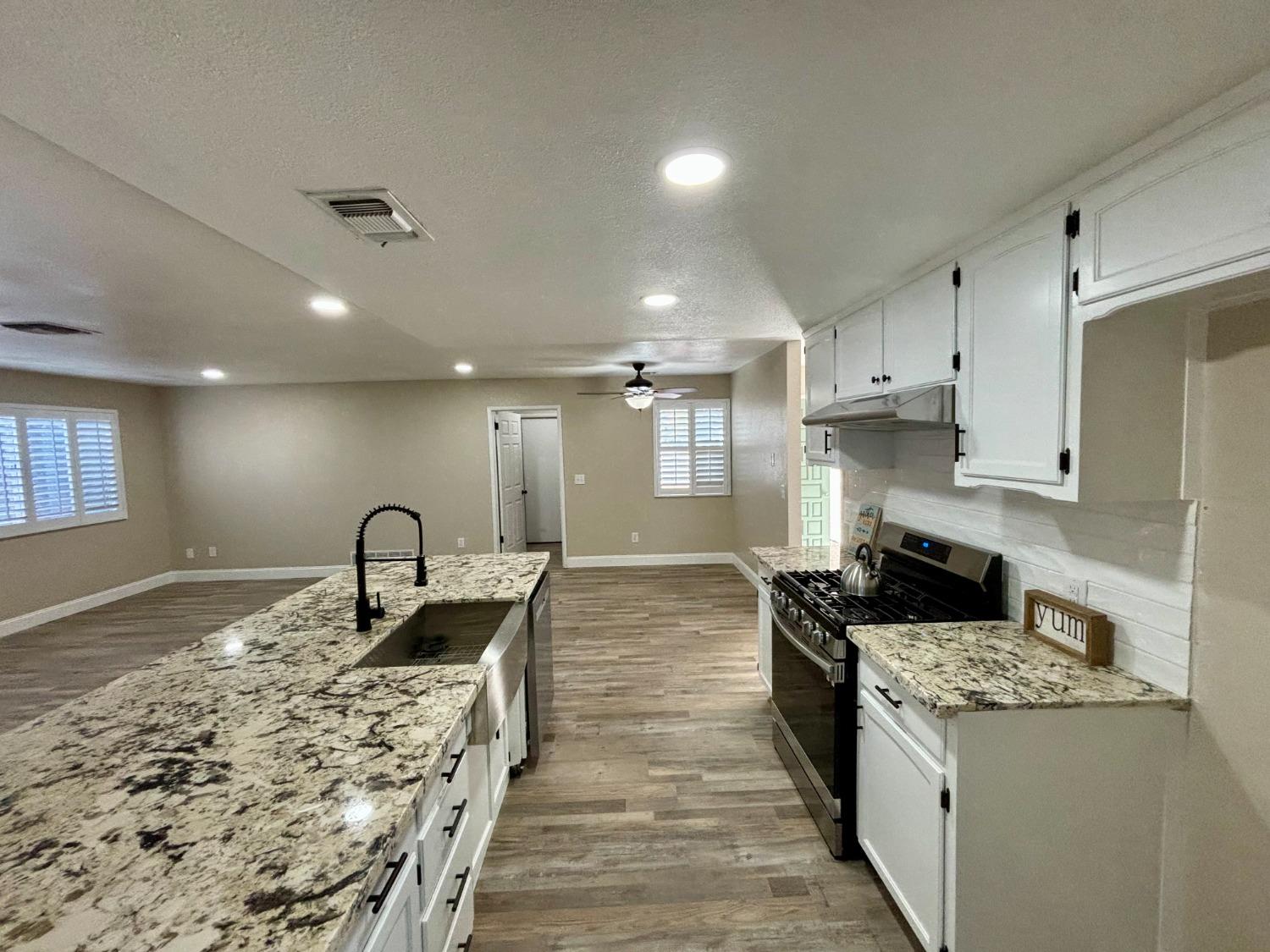910 Cedar Lane Lemoore, CA 93245 - Photo 16 of 32 a kitchen with kitchen island granite countertop a stove and a sink