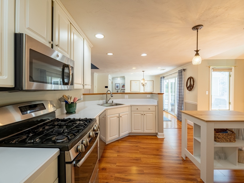 67 Tussock Brook Road, Unit 67 Duxbury, MA 02332 - Photo 17 of 39 a kitchen with stainless steel appliances kitchen island granite countertop a stove a sink dishwasher and a microwave oven with wooden floor