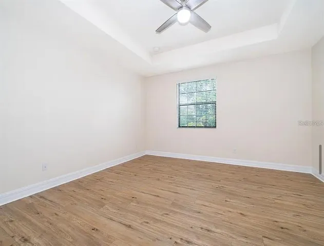 an empty room with wooden floor fan and windows