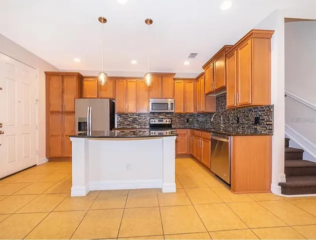 a kitchen with stainless steel appliances granite countertop a stove a sink and a refrigerator