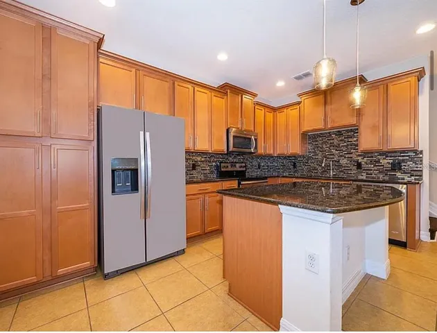 a kitchen with stainless steel appliances granite countertop a sink a stove a refrigerator a center island and cabinets