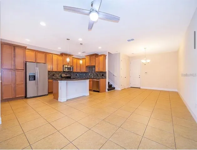 a view of a kitchen with stainless steel appliances kitchen island granite countertop a refrigerator and a stove top oven
