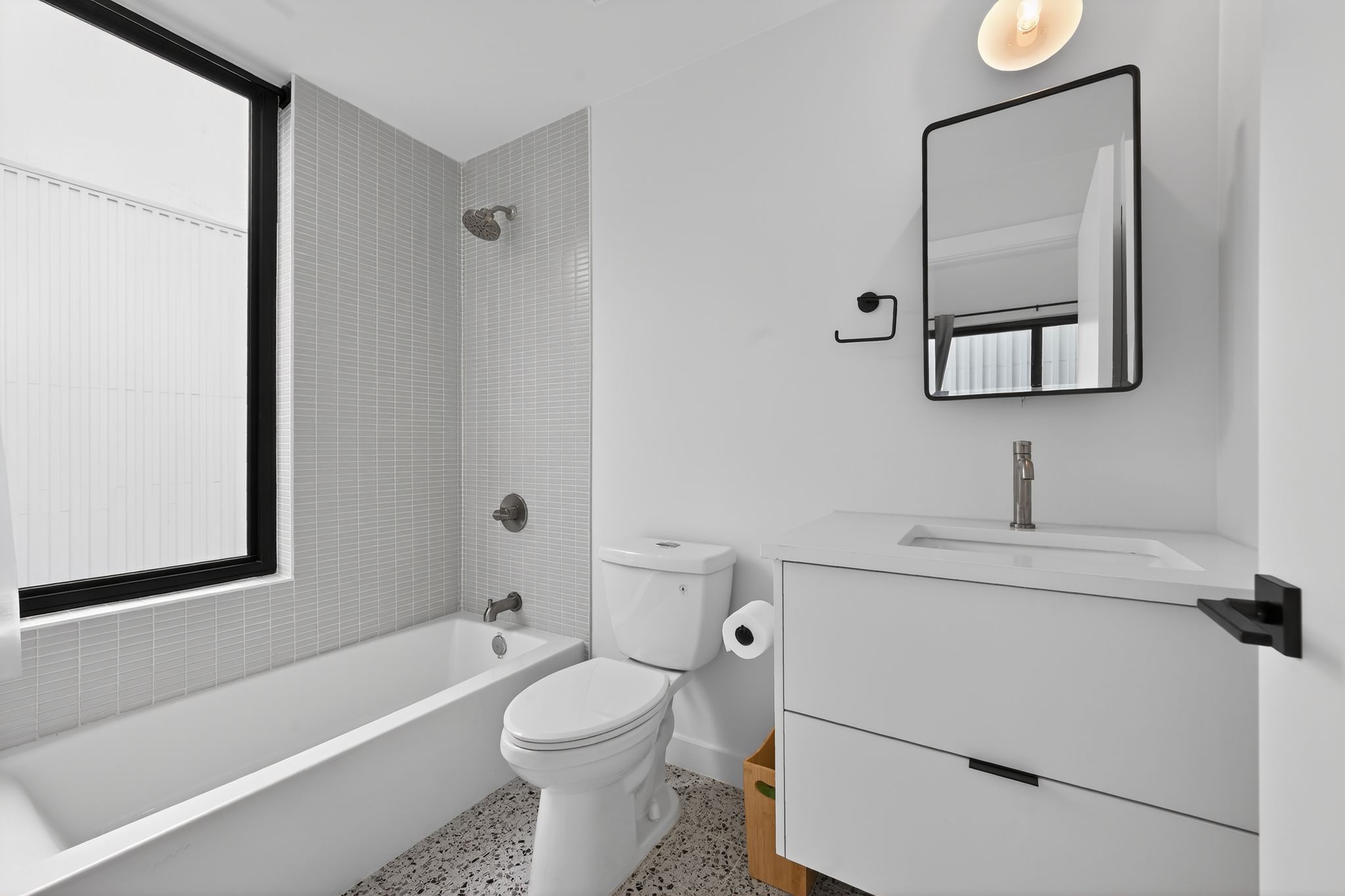 1206 Luna Street, Unit 2 Austin, TX 78721 - Photo 26 of 30 Bathroom featuring a white vanity with a rectangular sink, a framed mirror, a toilet, and a bathtub with tiled walls