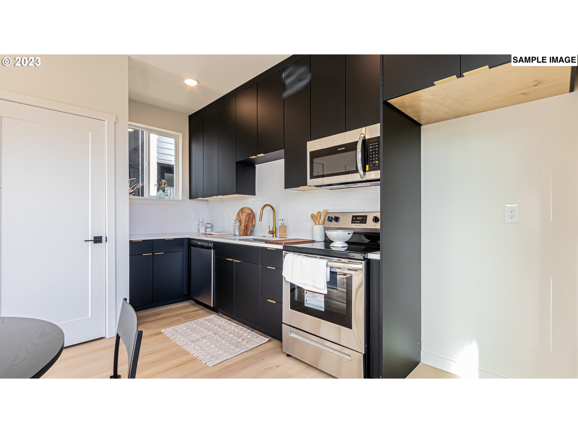 12063 Southeast Oak Street Portland, OR 97216 - Photo 4 of 11 a kitchen with stainless steel appliances kitchen island granite countertop a refrigerator and a sink