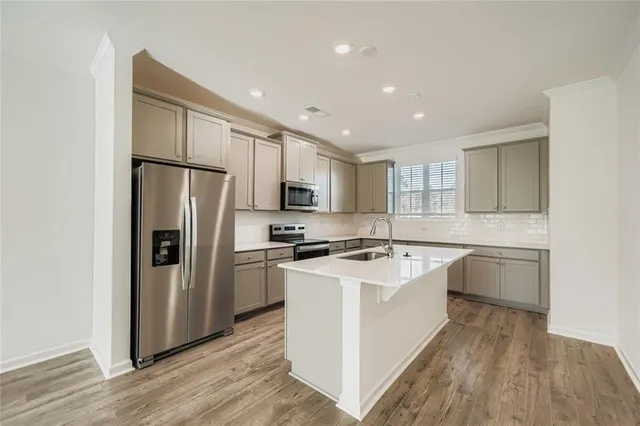 a kitchen with a refrigerator a sink dishwasher with a stove and wooden floor