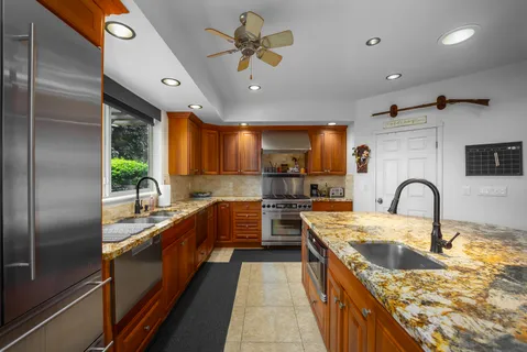 a large kitchen with stainless steel appliances granite countertop a sink a counter space and cabinets