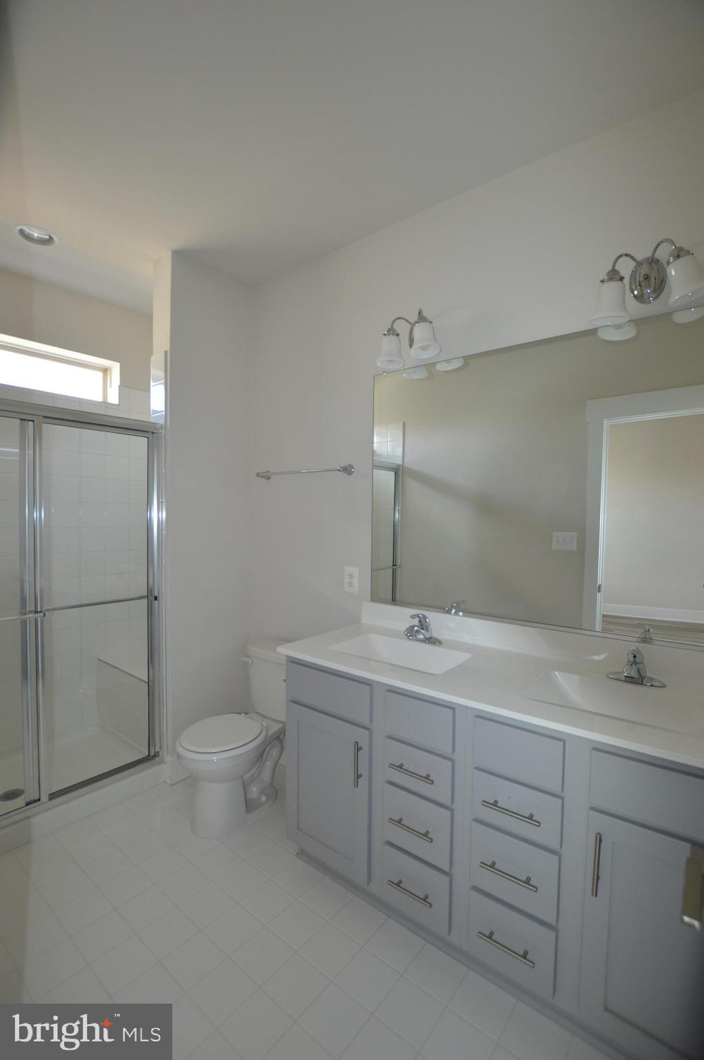 7927 Wormans Mill Road Frederick, MD 21701 - Photo 9 of 17 a spacious bathroom with a double vanity sink a toilet and a mirror