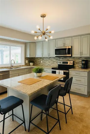 a kitchen with stainless steel appliances granite countertop a stove a sink a microwave a dining table and chairs with wooden floor