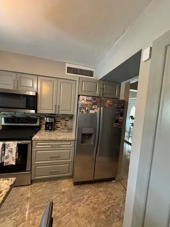 a view of a refrigerator in kitchen and an empty room