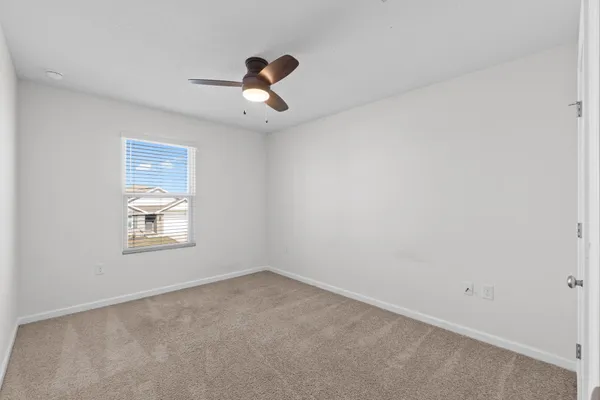 an empty room with a window and a fan