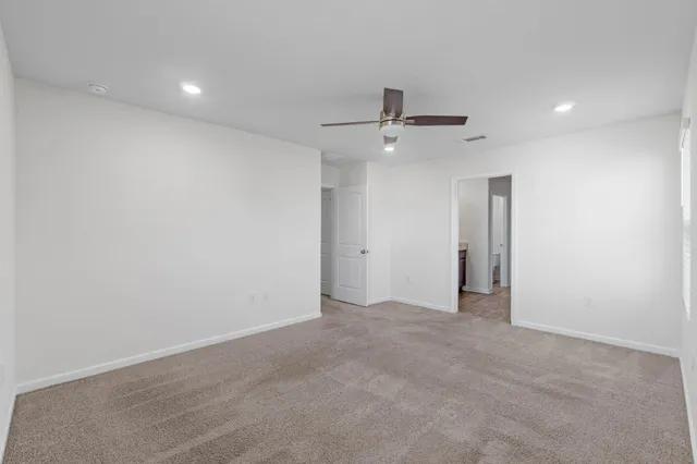 an empty room with ceiling fan and windows