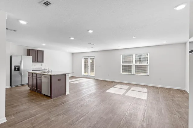 a living room with stainless steel appliances kitchen island hardwood floor and a large window
