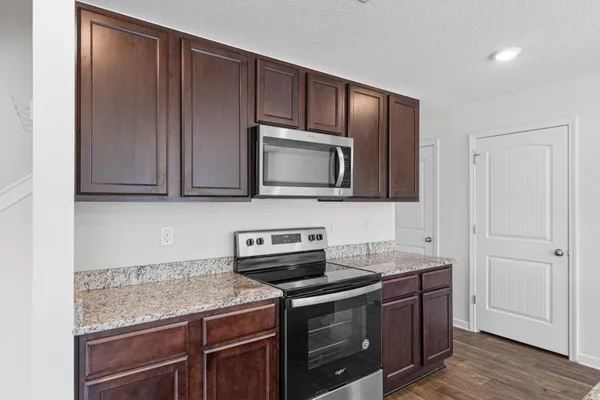a kitchen with stainless steel appliances granite countertop wooden cabinets and a stove top oven