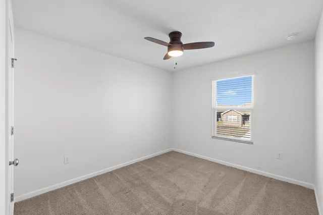 an empty room with a window and a ceiling fan