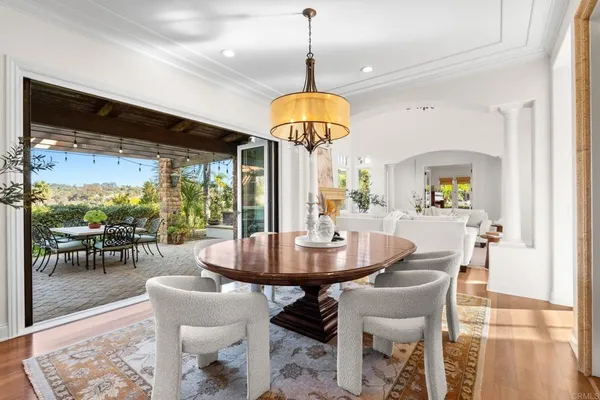 a dining room with wooden floor a chandelier a wooden table and chairs