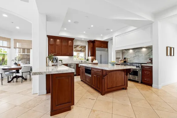 a kitchen with stainless steel appliances granite countertop wooden cabinets a sink a stove a dining table and chairs