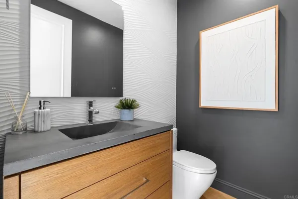 a bathroom with a granite countertop sink and a toilet