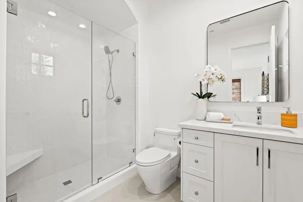 a bathroom with a toilet a sink a mirror and shower