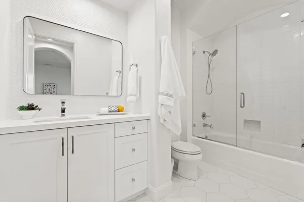 a bathroom with a double vanity sink toilet mirror and shower