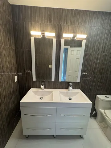 a bathroom with a sink a toilet a mirror and shower