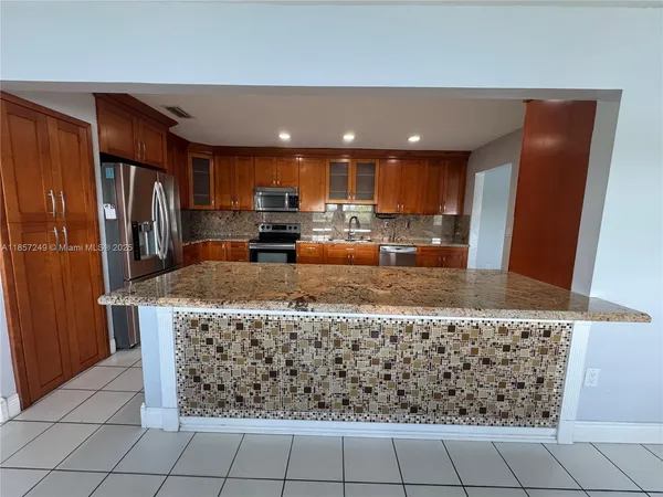 a kitchen with granite countertop a stove a sink and a refrigerator