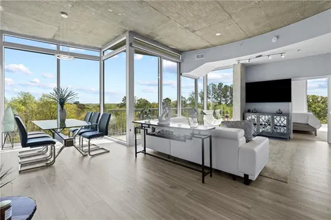 a living room with furniture floor to ceiling window hardwood floor and a flat screen tv