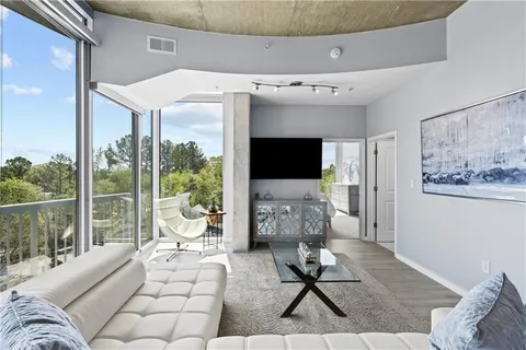 a living room with furniture a flat screen tv and a floor to ceiling window