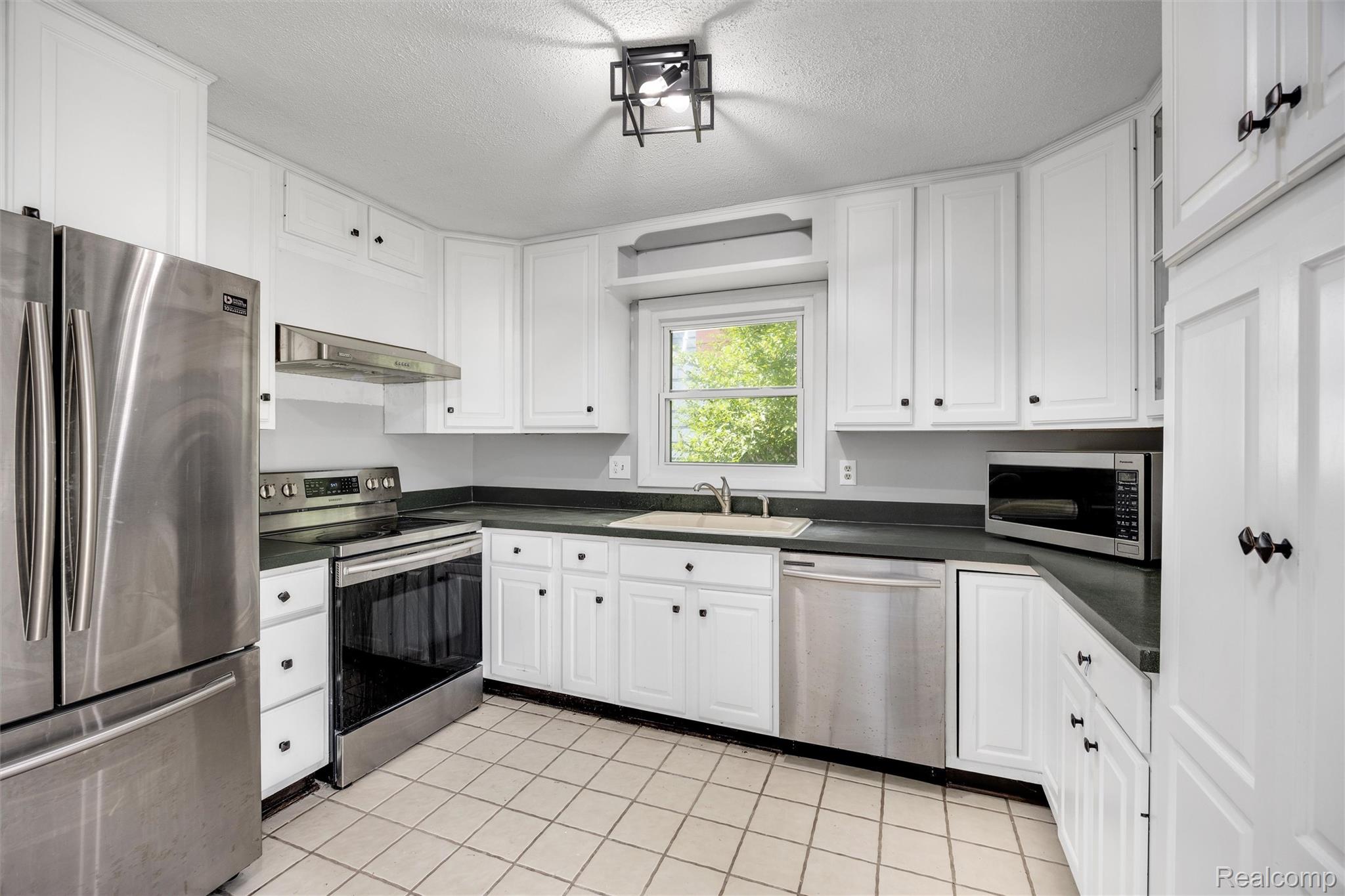4942 Butler Drive Troy, MI 48085 - Photo 8 of 33 Kitchen featuring white cabinetry, dark countertops, tile flooring, and stainless steel appliances including a refrigerator, range, and dishwasher