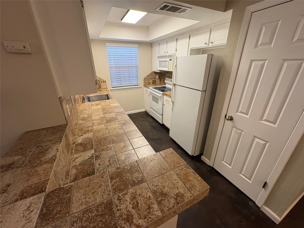 8713 Clearbrook Trail, Unit A Austin, TX 78729 - Photo 11 of 22 a kitchen with granite countertop a refrigerator and a sink